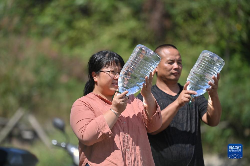 楊寧（左）在查看村民剛剛采集的水樣，為山泉水引水工程做準備（10月8日攝）。新華社記者 黃孝邦 攝